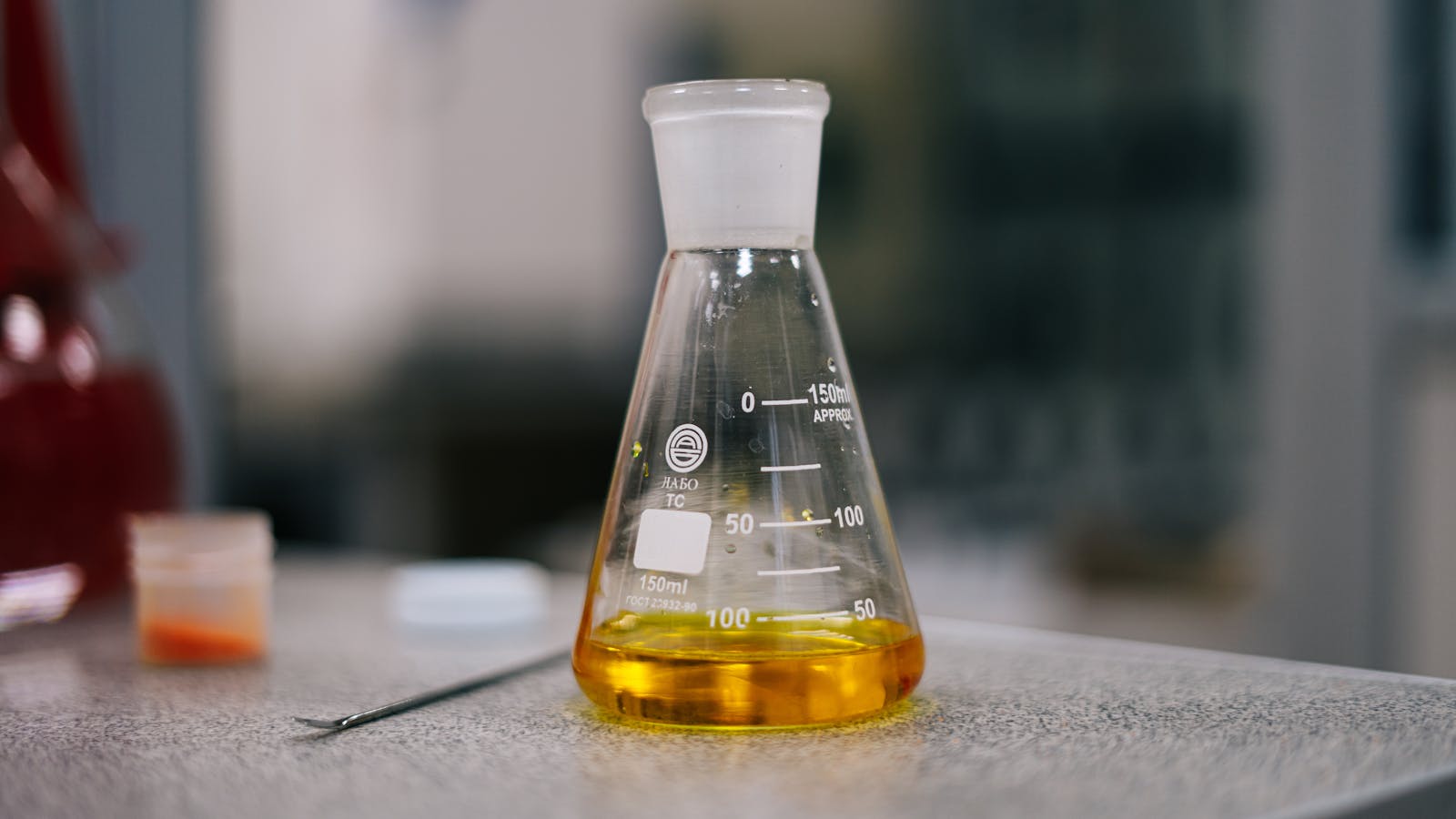 Erlenmeyer flask containing yellow liquid in a laboratory setting