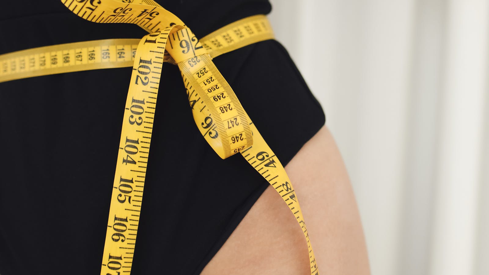 Yellow tape measure wrapped around a person's waist