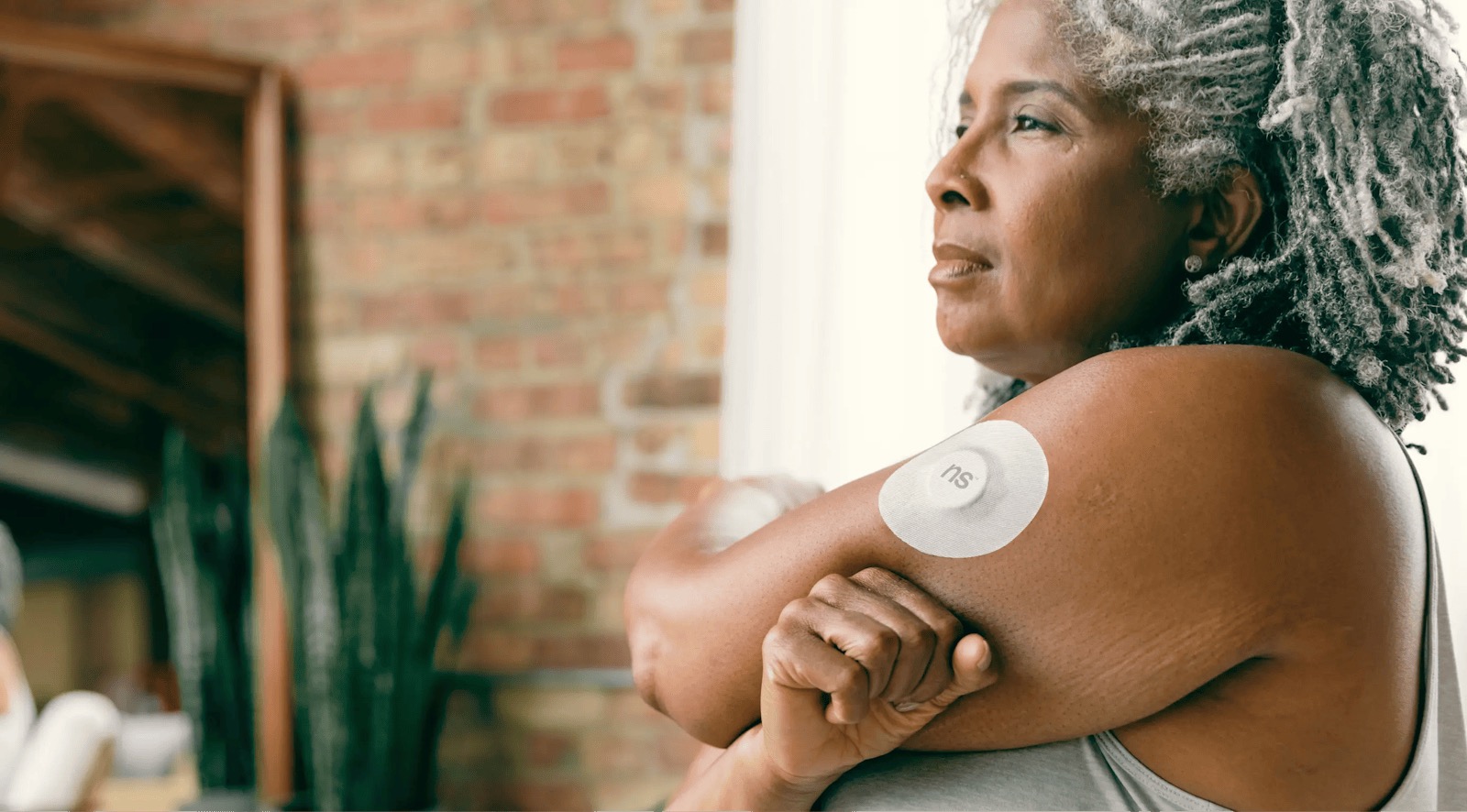Continuous glucose monitor sensor adhered to an upper arm