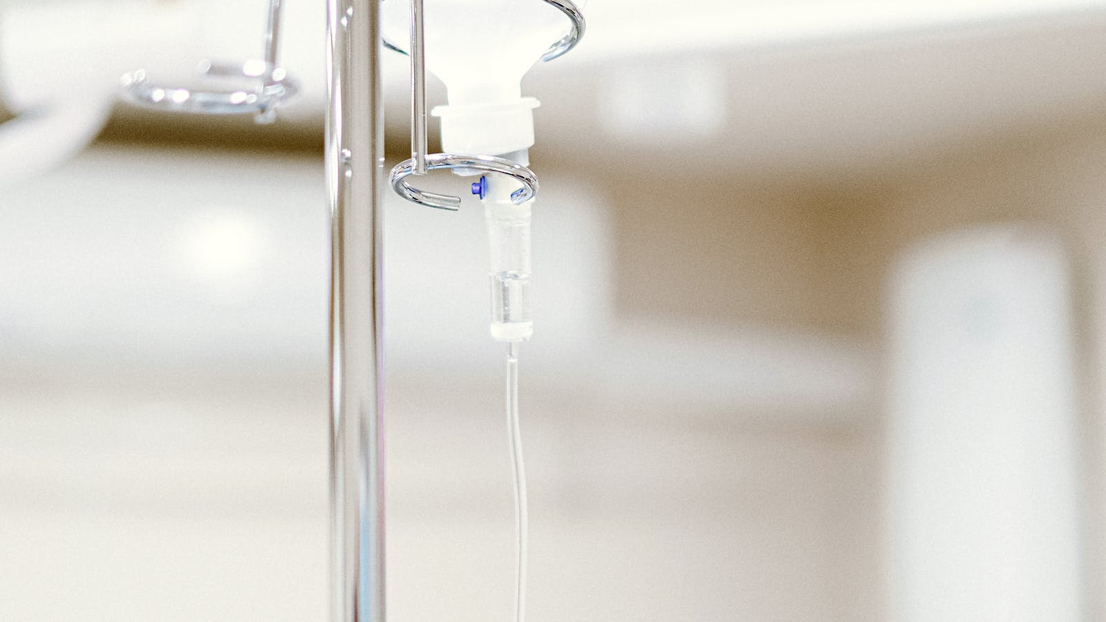 Close-up of an IV fluid bag and infusion line hanging on a clinical pole in a sterile hospital setting