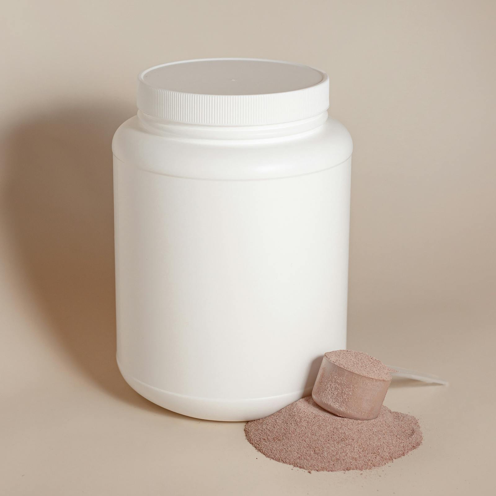 Container of white protein powder with a measuring scoop