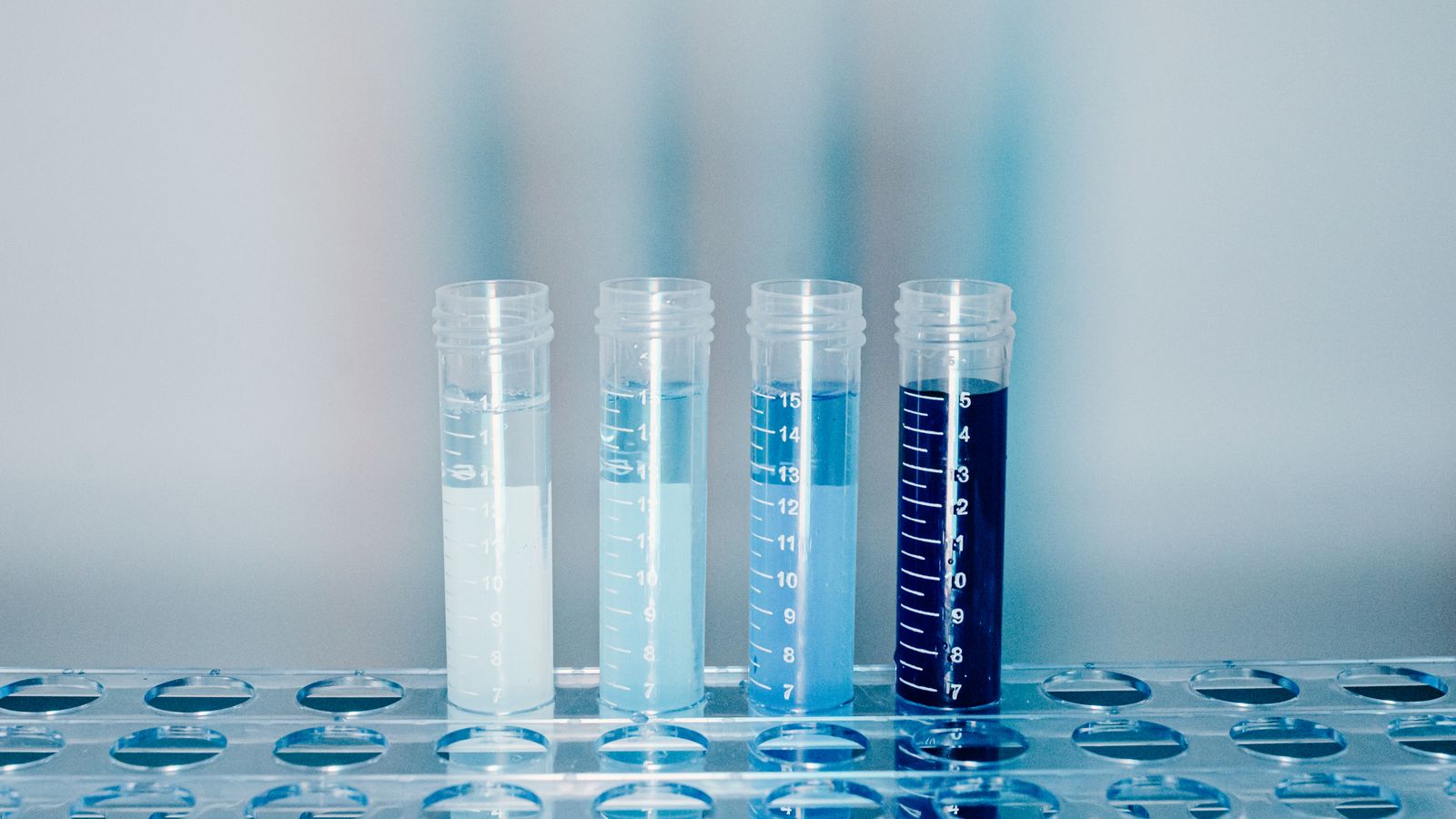 Rows of clear test tubes holding blue liquid in a laboratory, evoking the blue-green copper complex of GHK-Cu and the research evidence behind it