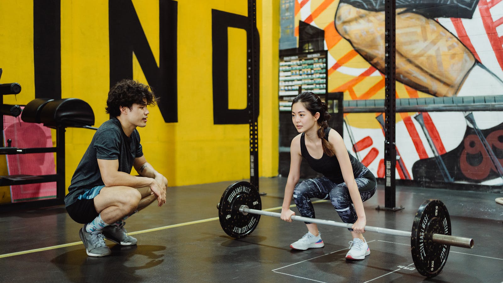 Person lifting dumbbells with a coach's guidance in a gym
