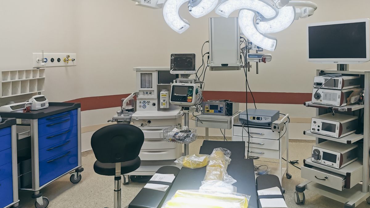 An empty, brightly lit modern operating room with surgical lights and equipment
