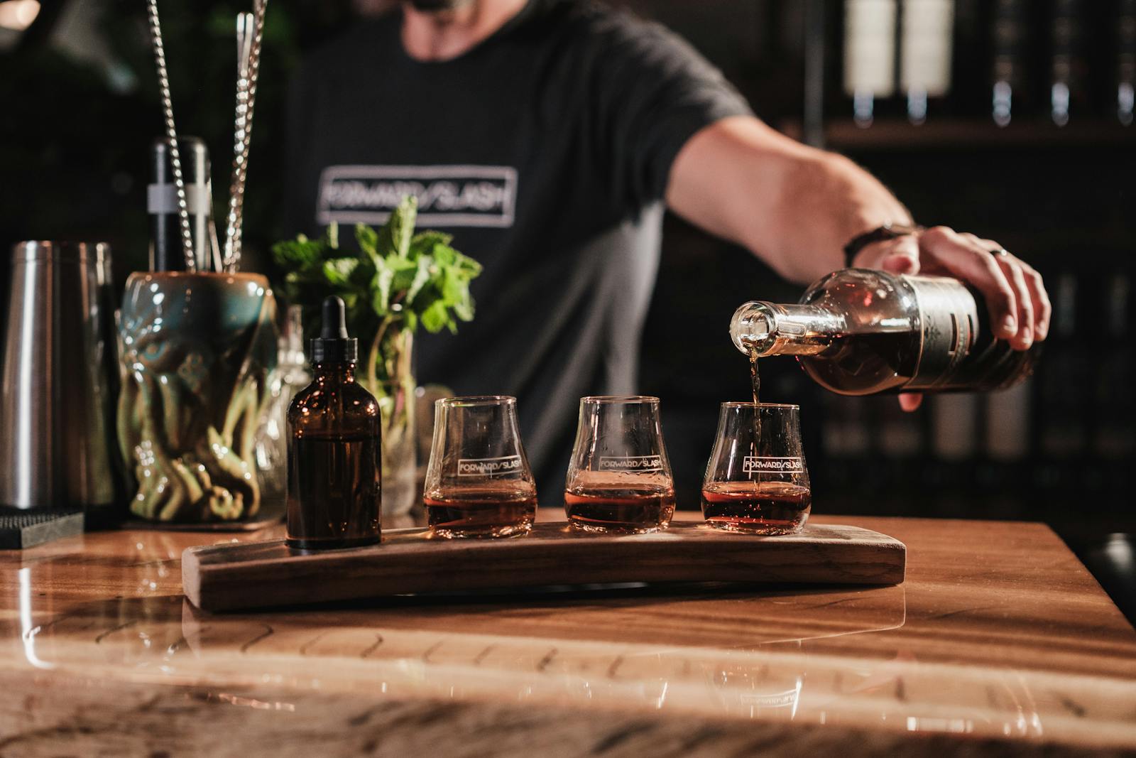 Whiskey being poured into glasses on a bar counter