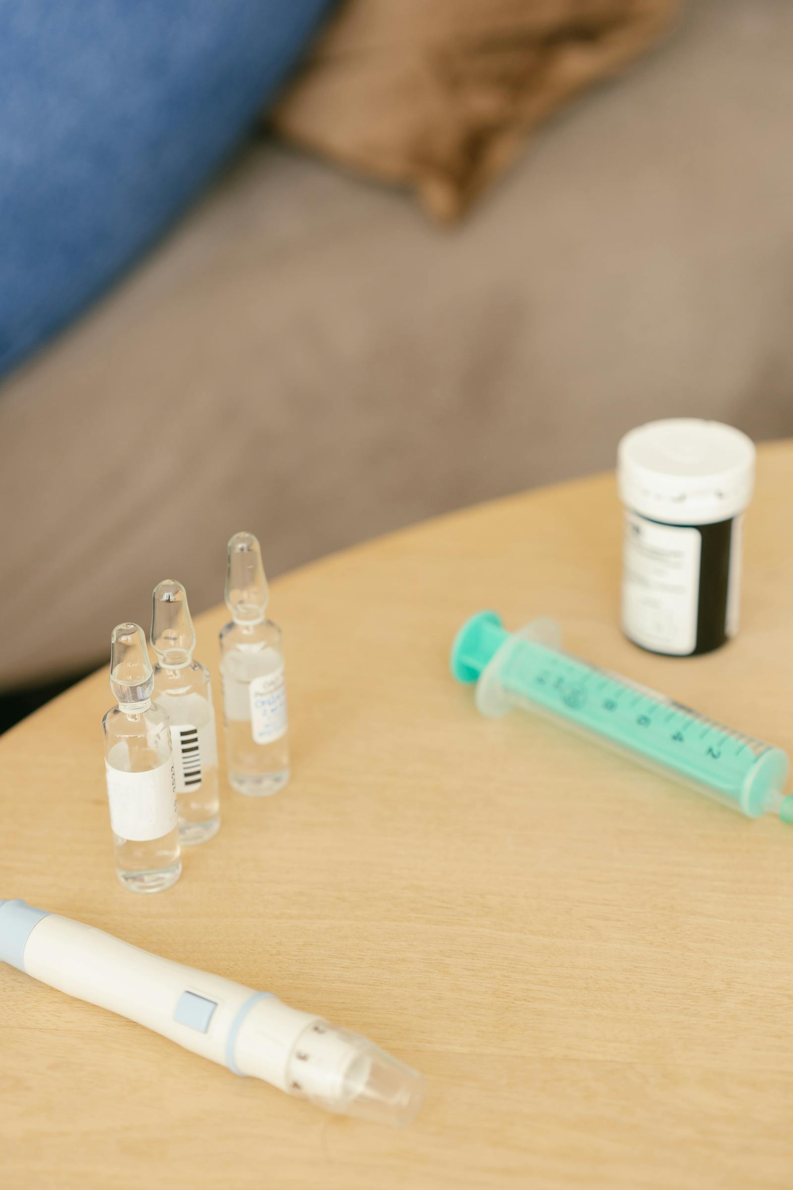 Close-up of an injection pen and glass ampoules arranged on a wooden surface