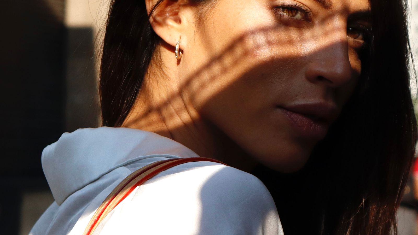 Close-up of a woman's face in natural sunlight with shadow falling across her cheek and jaw