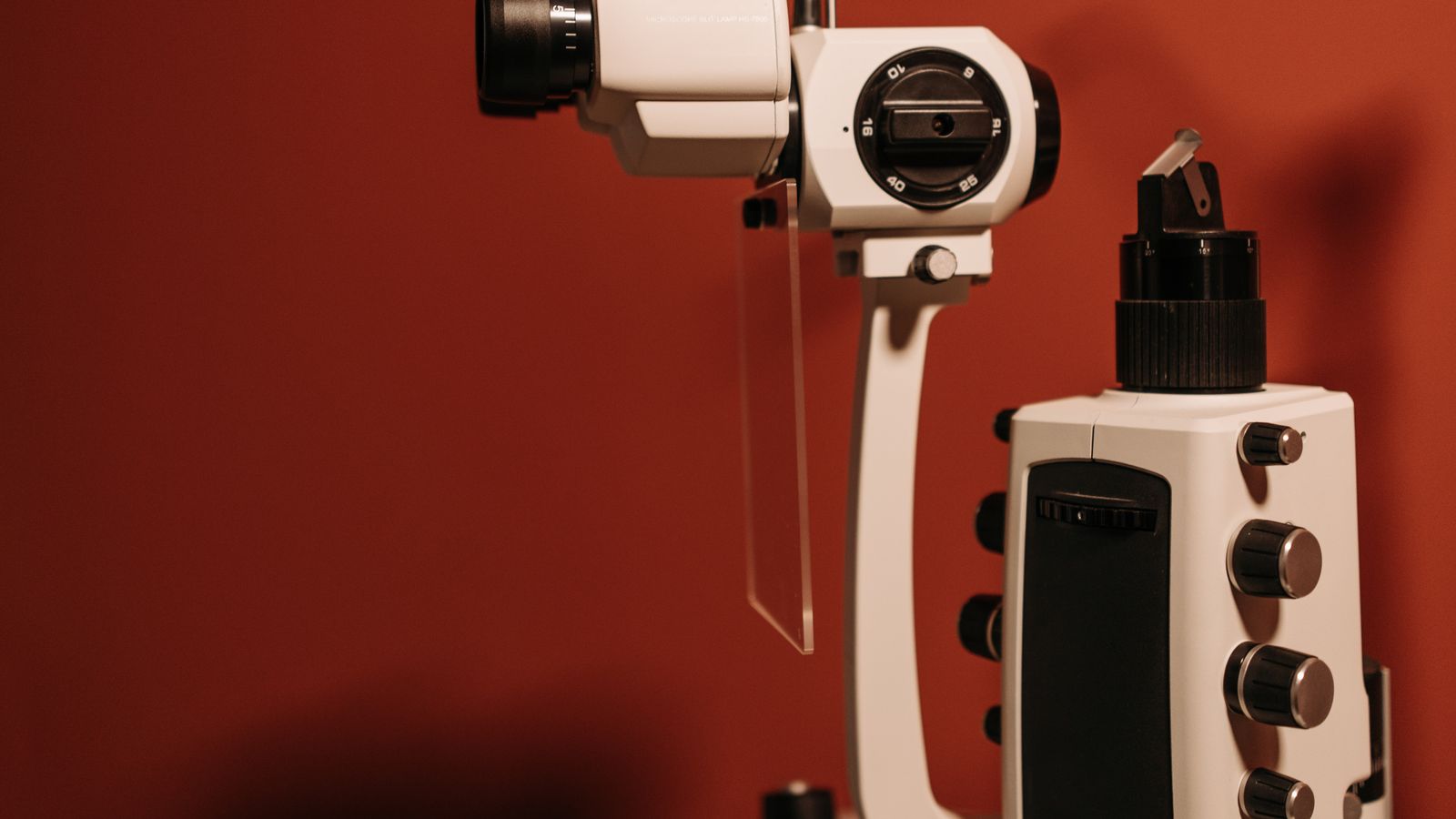 A slit lamp, the microscope-and-light instrument an eye doctor uses to examine the eye, standing in a clinical exam room