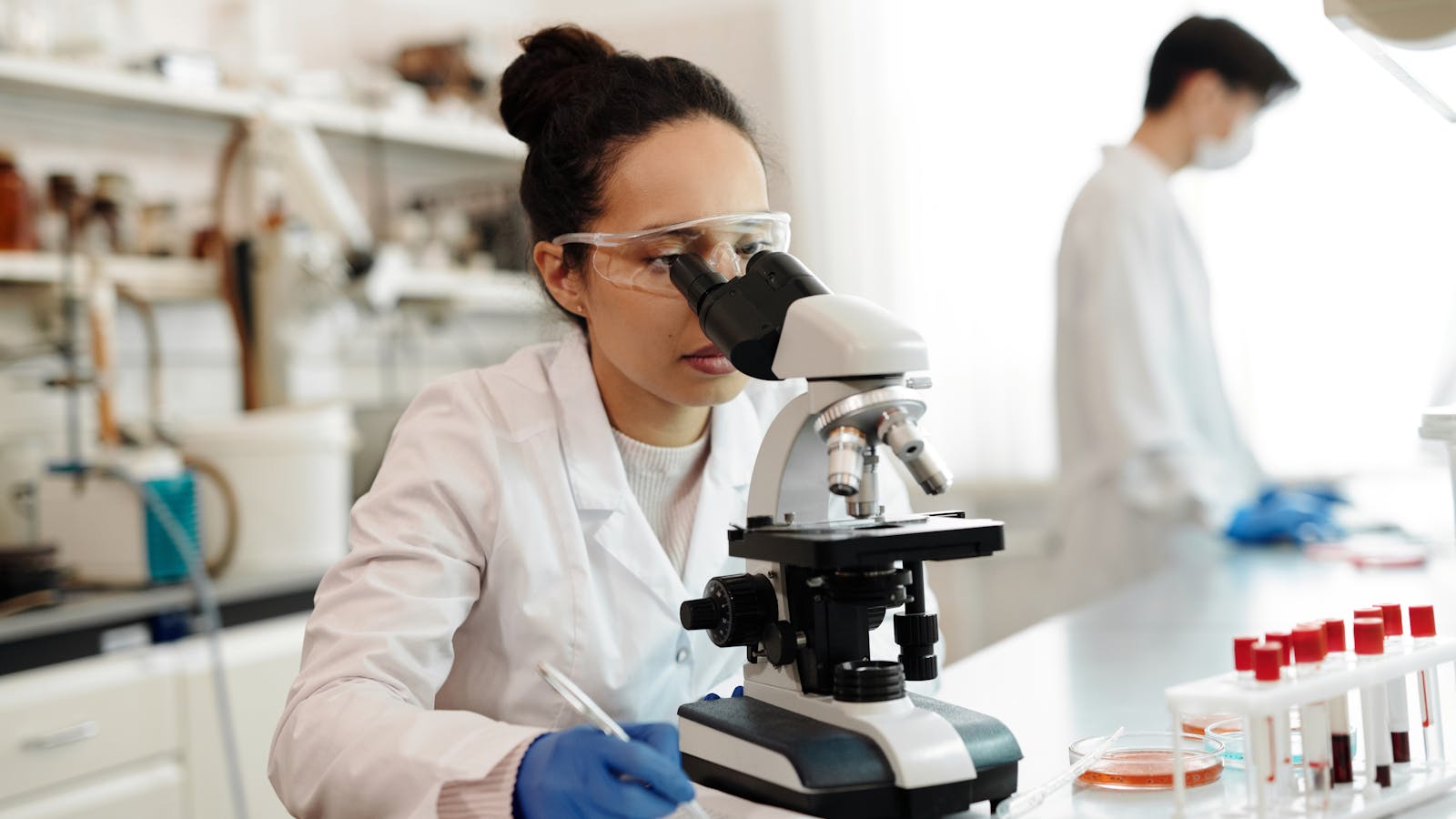 Female scientist in a white lab coat using a microscope